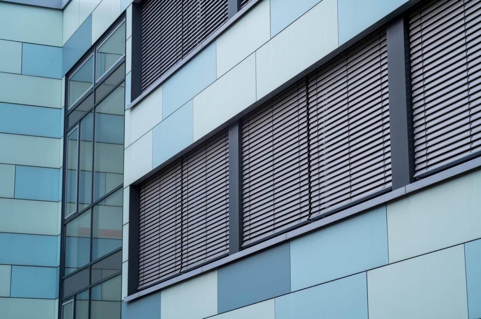Modern blue-paneled building with horizontal blinds