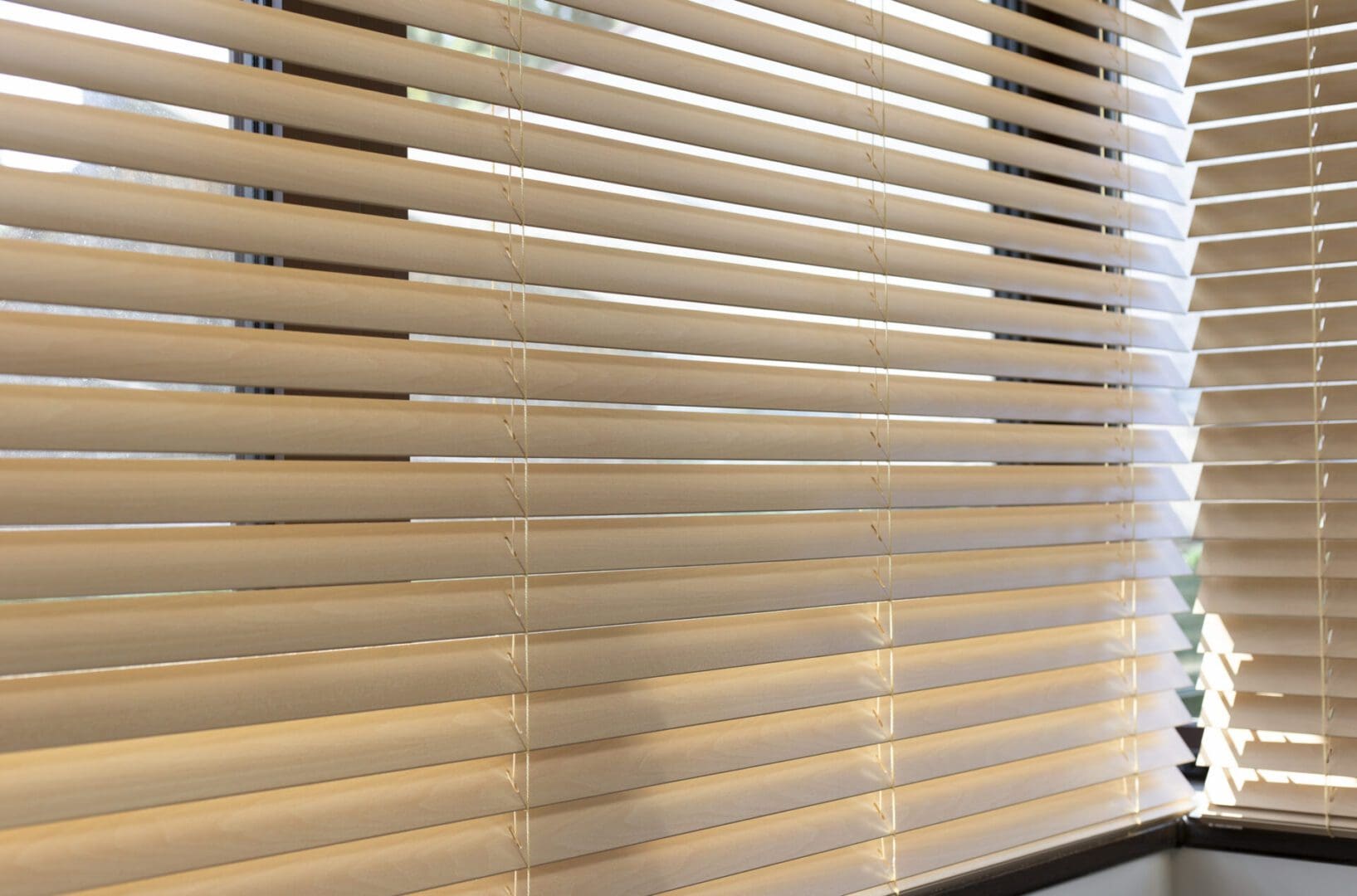Sunlit beige window blinds with corner view