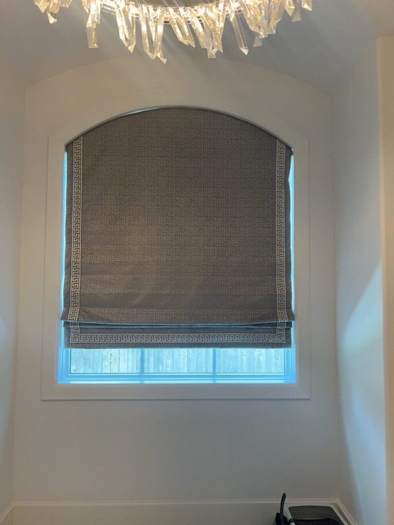 arched window with patterned gray Roman shade