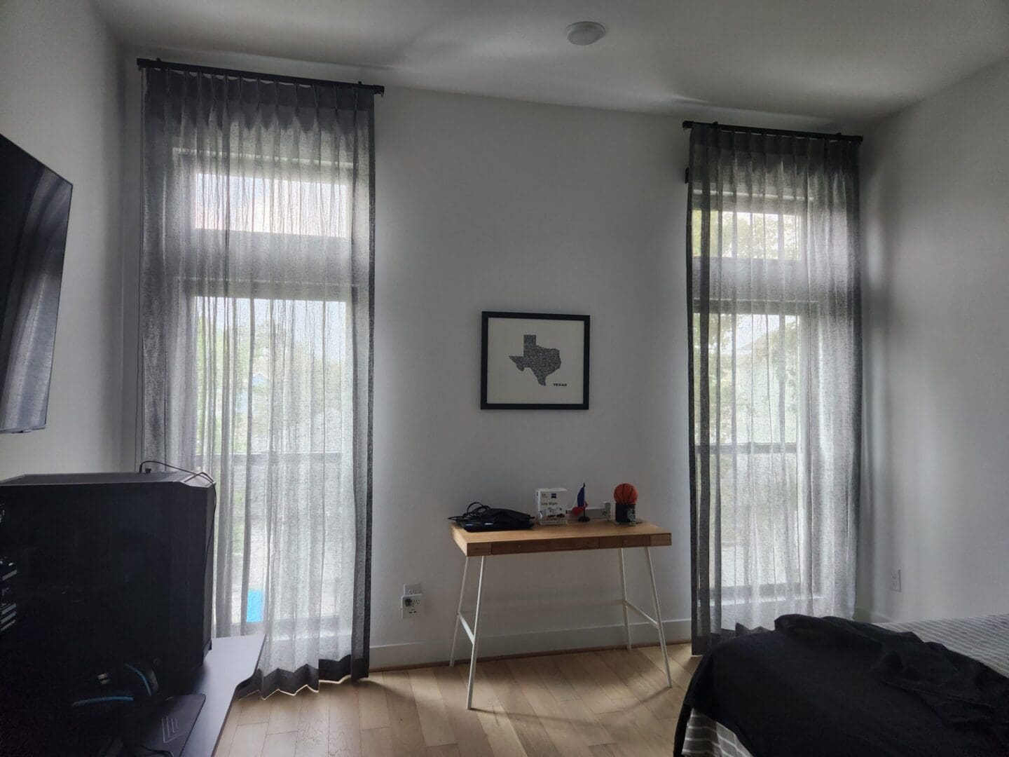 Bedroom with sheer curtains and Texas art