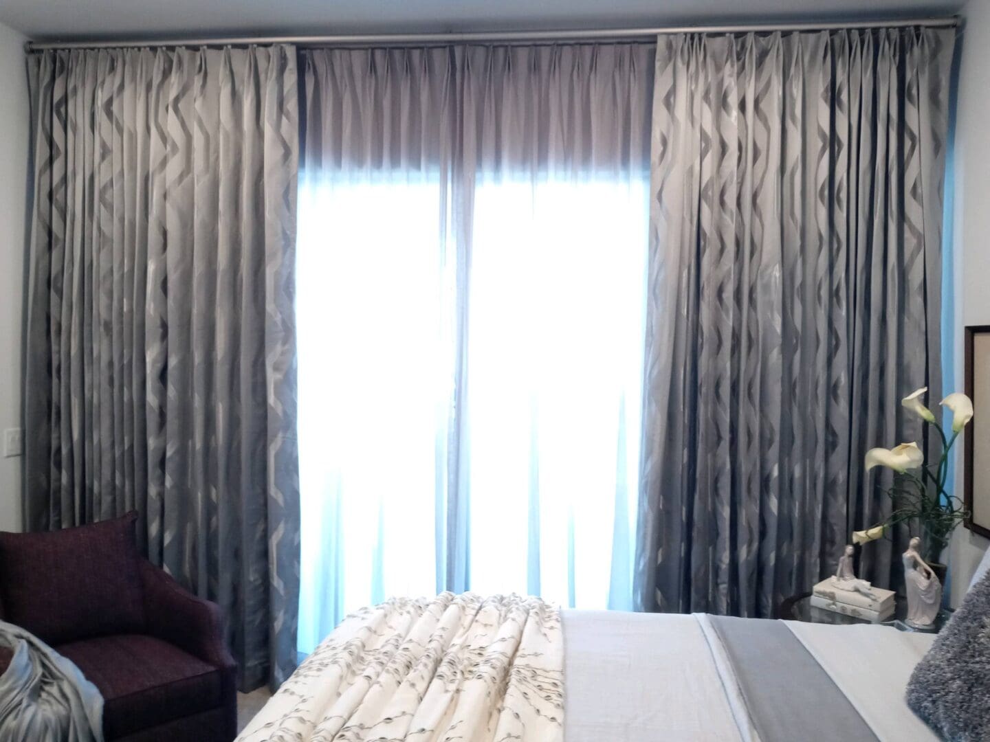 Sunlit bedroom with gray patterned curtains
