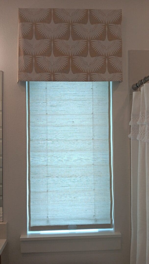 Bathroom window with patterned valance and roman shade