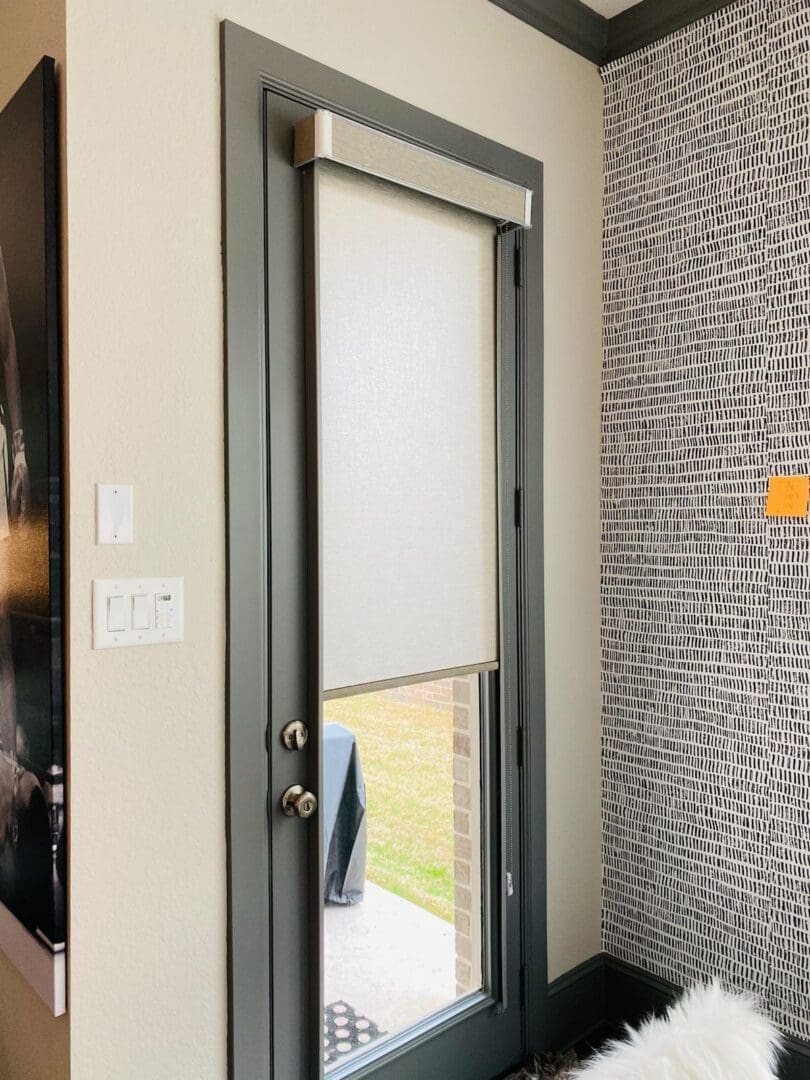 Gray-framed glass door with white roller shade